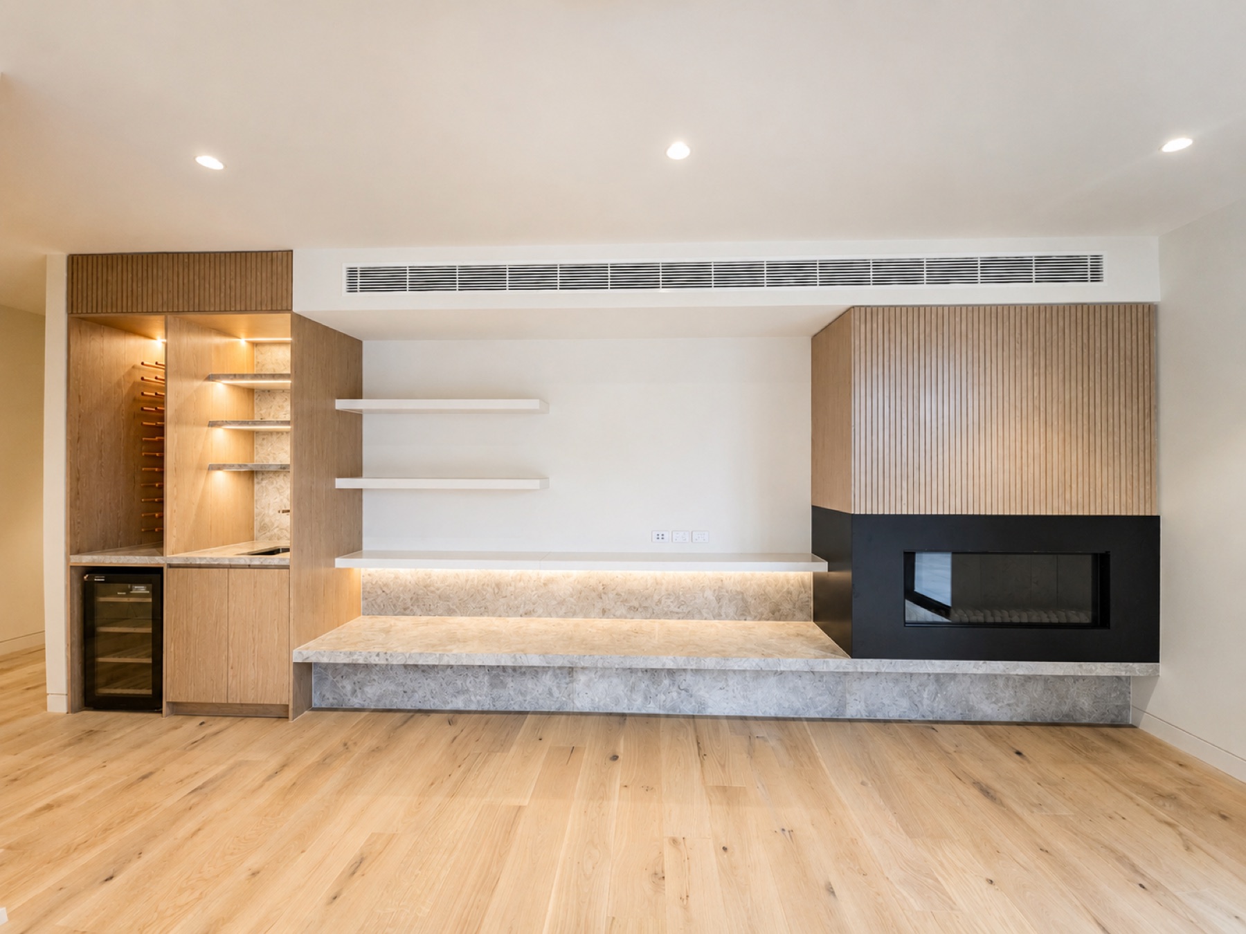 Custom oak entertainment unit with integrated fireplace and illuminated display cabinetry